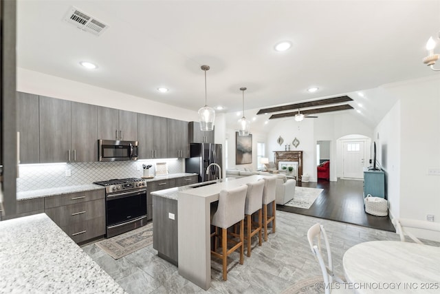 2621 S Catalayah Ln, Claremore, OK 74019 - kitchen with appliances with stainless steel finishes, a breakfast bar area, arched walkways, tasteful backsplash, and open floor plan