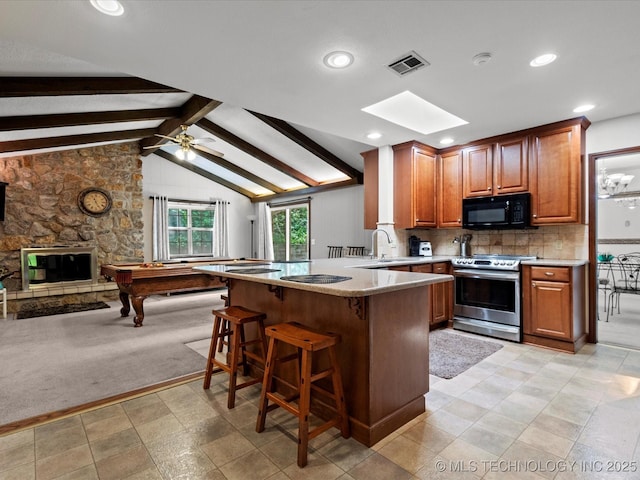 1800 SE Polaris Dr, Bartlesville, OK 74006 - kitchen featuring stainless steel electric range, black microwave, a peninsula, open floor plan, and a kitchen breakfast bar