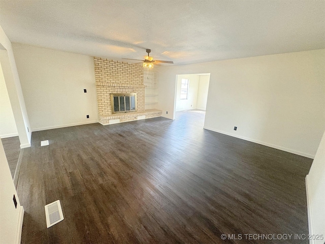 26037 S 520th Rd, Park Hill, OK 74451 - unfurnished living room with a ceiling fan, dark wood-type flooring, a brick fireplace, baseboards, and a textured ceiling