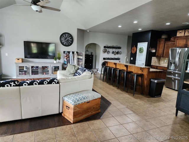 14201 E 101st St, Owasso, OK 74055 - living room with arched walkways, a ceiling fan, vaulted ceiling, light tile patterned floors, and recessed lighting