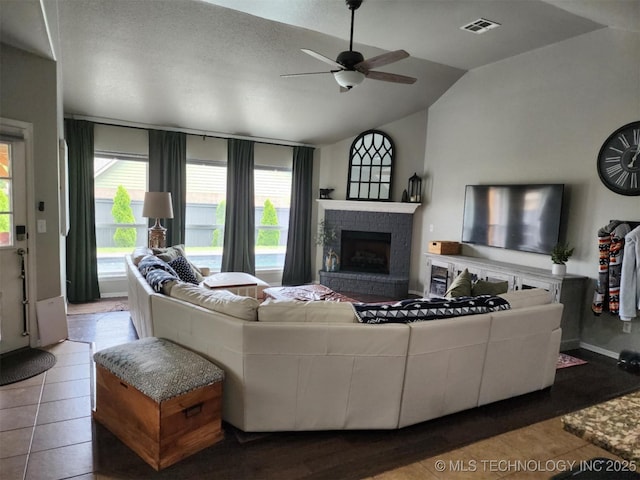 14201 E 101st St, Owasso, OK 74055 - tiled living room featuring vaulted ceiling, a fireplace with raised hearth, and ceiling fan