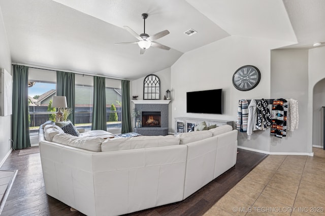 14201 E 101st St, Owasso, OK 74055 - living area featuring vaulted ceiling, a lit fireplace, a ceiling fan, baseboards, and wood finished floors