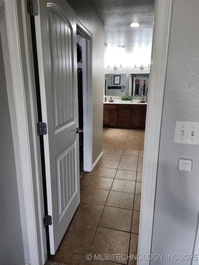 14201 E 101st St, Owasso, OK 74055 - hallway featuring tile patterned flooring, a textured wall, and a sink