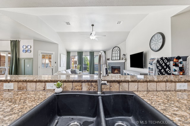 14201 E 101st St, Owasso, OK 74055 - kitchen with lofted ceiling, open floor plan, a sink, a ceiling fan, and a warm lit fireplace