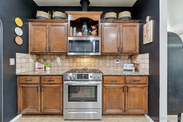 14201 E 101st St, Owasso, OK 74055 - kitchen featuring appliances with stainless steel finishes, decorative backsplash, baseboards, and brown cabinets