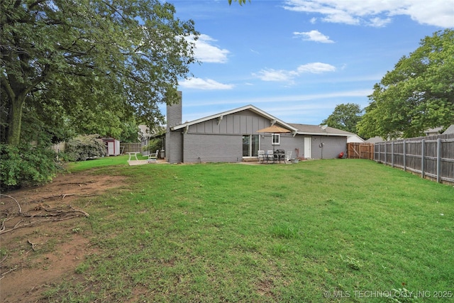 7630 E 54th Pl, Tulsa, OK 74145 - rear view of house featuring a chimney, a storage unit, a fenced backyard, brick siding, and board and batten siding