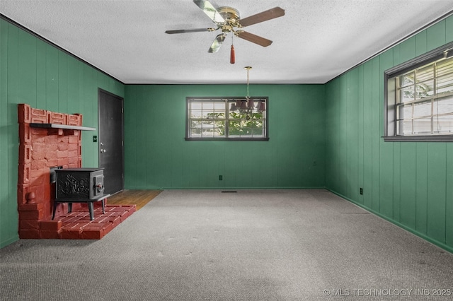 2728 E 13th Pl, Tulsa, OK 74104 - unfurnished living room featuring healthy amount of natural light, a wood stove, carpet, a textured ceiling, and ceiling fan