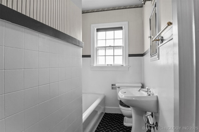 2728 E 13th Pl, Tulsa, OK 74104 - bathroom featuring toilet, a tub, wallpapered walls, and baseboards