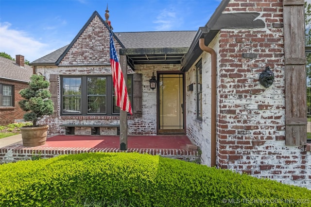 2728 E 13th Pl, Tulsa, OK 74104 - doorway to property featuring brick siding and a shingled roof