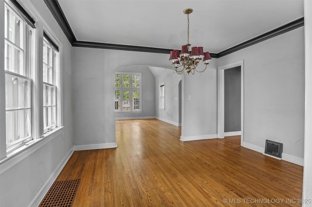 2728 E 13th Pl, Tulsa, OK 74104 - unfurnished room with arched walkways, a chandelier, ornamental molding, baseboards, and wood finished floors