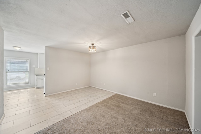 2761 S 134th E Ave, Tulsa, OK 74134 - spare room with a textured ceiling, light tile patterned floors, baseboards, and light colored carpet