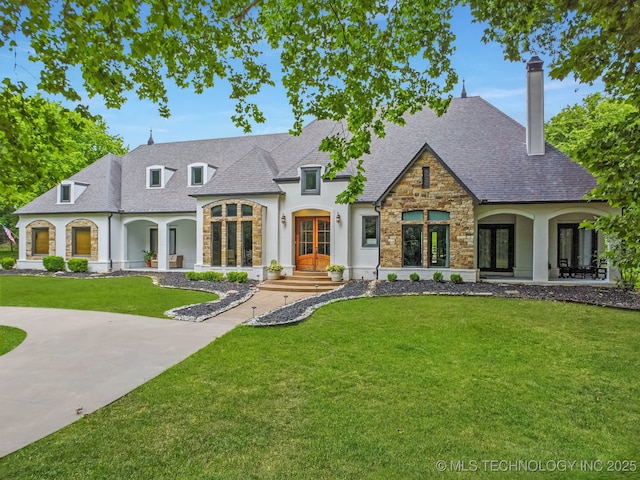 9914 S Garnett Rd, Broken Arrow, OK 74012 - french country home with french doors, stone siding, a front yard, a chimney, and stucco siding