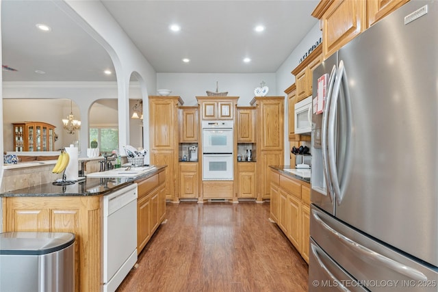 2508 S 14th St, Mcalester, OK 74501 - kitchen with white appliances, arched walkways, recessed lighting, wood finished floors, and a sink