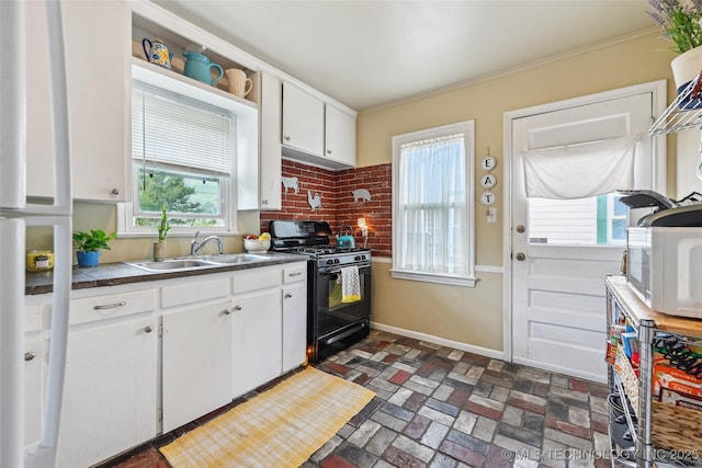 3508 E 30th St, Tulsa, OK 74114 - kitchen with black range with gas stovetop, a sink, white cabinets, brick patterned flooring, and baseboards