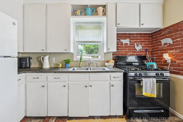 3508 E 30th St, Tulsa, OK 74114 - kitchen featuring black range with gas stovetop, a sink, freestanding refrigerator, white cabinetry, and brick wall