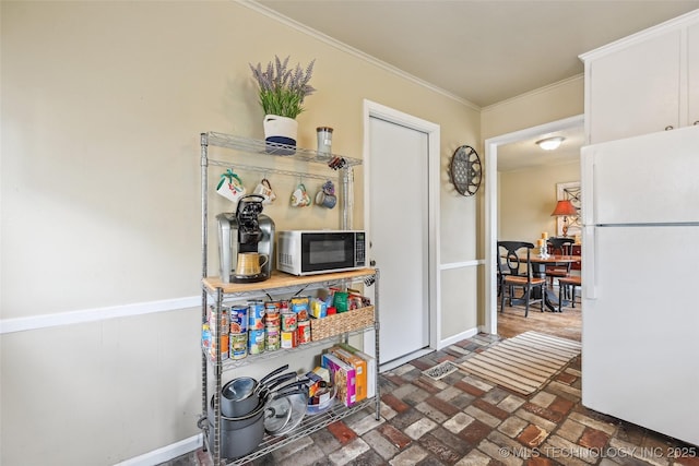 3508 E 30th St, Tulsa, OK 74114 - kitchen with freestanding refrigerator, black microwave, brick flooring, crown molding, and baseboards