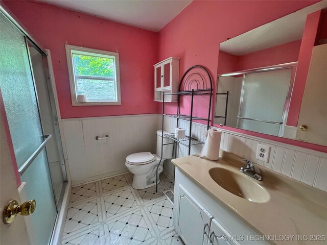 5006 S 449th Ave W, Jennings, OK 74038 - full bathroom featuring a wainscoted wall, a shower with door, toilet, vanity, and tile patterned floors