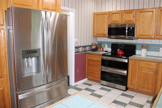 7023 Myall Rd, Lone Grove, OK 73443 - kitchen with stainless steel appliances, tile countertops, wallpapered walls, backsplash, and light flooring