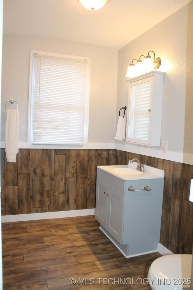 400 E Comanche, Mcalester, OK 74501 - bathroom featuring vanity, wood finished floors, toilet, a wainscoted wall, and wood walls