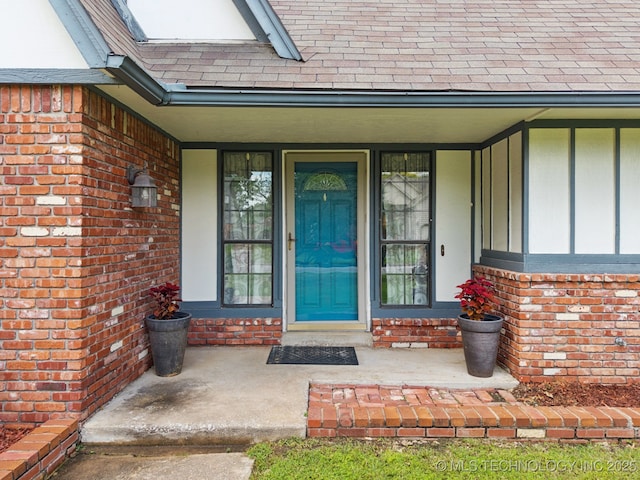 11029 E 66th St, Tulsa, OK 74133 - doorway to property featuring a shingled roof, brick siding, and covered porch
