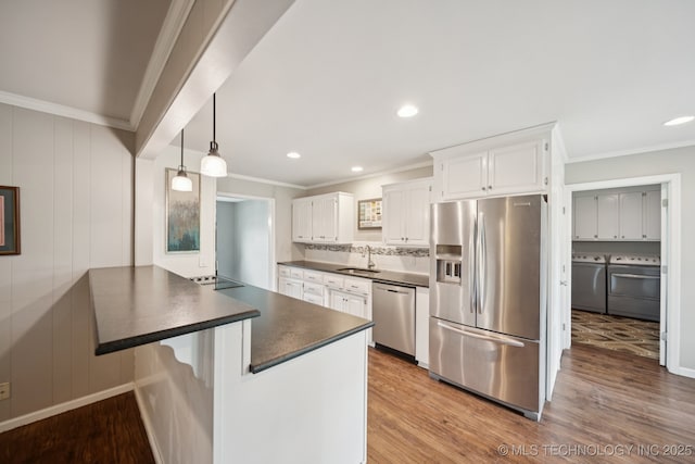 11029 E 66th St, Tulsa, OK 74133 - kitchen featuring appliances with stainless steel finishes, washer and dryer, dark countertops, ornamental molding, and a peninsula