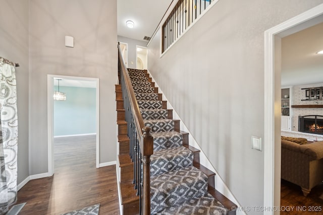 11029 E 66th St, Tulsa, OK 74133 - staircase featuring wood finished floors, a fireplace, and a towering ceiling