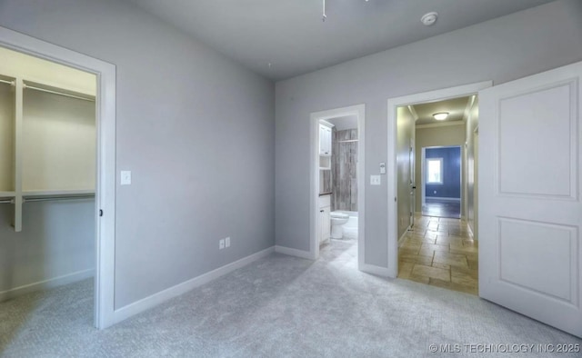 3816 E 117th Pl, Tulsa, OK 74137 - unfurnished bedroom featuring baseboards, carpet floors, a spacious closet, connected bathroom, and stone tile flooring