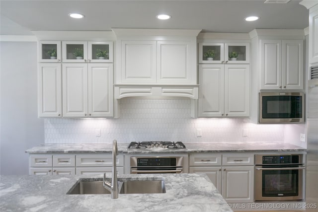 3816 E 117th Pl, Tulsa, OK 74137 - kitchen with appliances with stainless steel finishes, white cabinets, light stone countertops, glass insert cabinets, and recessed lighting