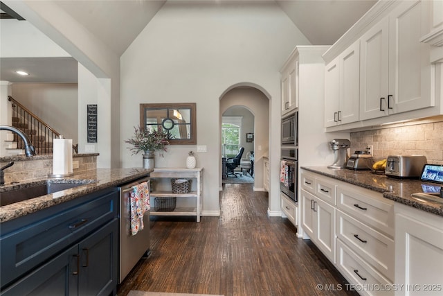 4472 S 169th E Ave, Tulsa, OK 74134 - kitchen with stainless steel appliances, a sink, arched walkways, white cabinetry, and decorative backsplash