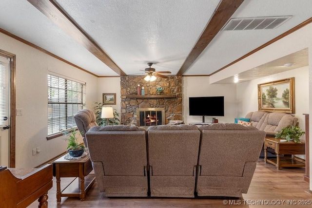 2612 W Quincy St, Broken Arrow, OK 74012 - living area featuring a ceiling fan, wood finished floors, beamed ceiling, a stone fireplace, and crown molding