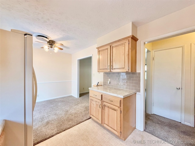 5641 S Newport Ave Unit 5641, Tulsa, OK 74105 - kitchen with freestanding refrigerator, light colored carpet, light countertops, light brown cabinetry, and a textured ceiling