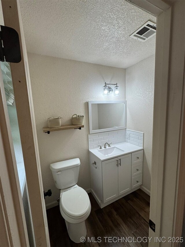 2752 Sawmill, Durant, OK 74701 - half bathroom with vanity, wood finished floors, a textured wall, a textured ceiling, and toilet