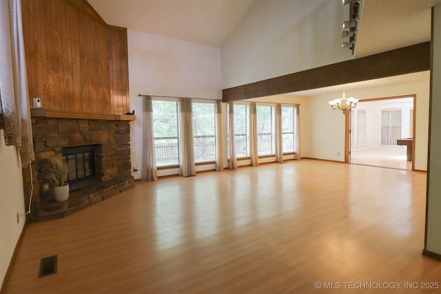 9337 S Lakewood Ave, Tulsa, OK 74137 - unfurnished living room with high vaulted ceiling, light wood-style flooring, a stone fireplace, and a chandelier