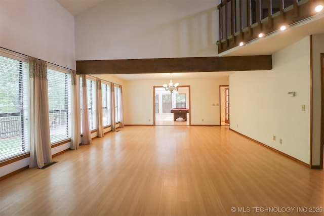 9337 S Lakewood Ave, Tulsa, OK 74137 - unfurnished living room with a chandelier, light wood finished floors, baseboards, beam ceiling, and a towering ceiling