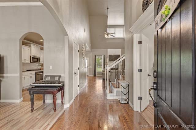 5006 S 164th E Ave, Tulsa, OK 74134 - foyer entrance with ceiling fan, light wood-style flooring, a towering ceiling, stairs, and arched walkways