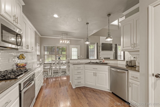 5006 S 164th E Ave, Tulsa, OK 74134 - kitchen with stainless steel appliances, a sink, decorative backsplash, white cabinetry, and a peninsula