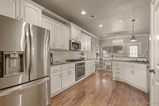 5006 S 164th E Ave, Tulsa, OK 74134 - kitchen featuring appliances with stainless steel finishes, a sink, ornamental molding, white cabinetry, and recessed lighting