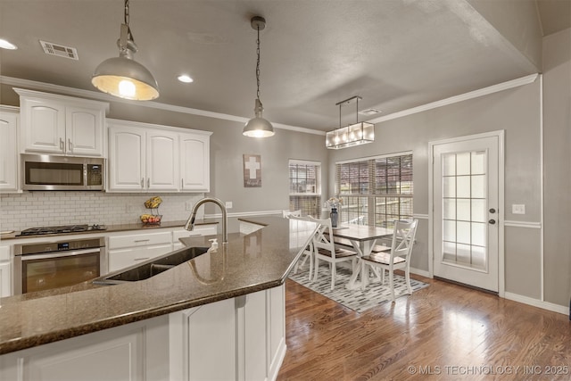 5006 S 164th E Ave, Tulsa, OK 74134 - kitchen featuring stainless steel appliances, a sink, white cabinetry, ornamental molding, and dark stone counters