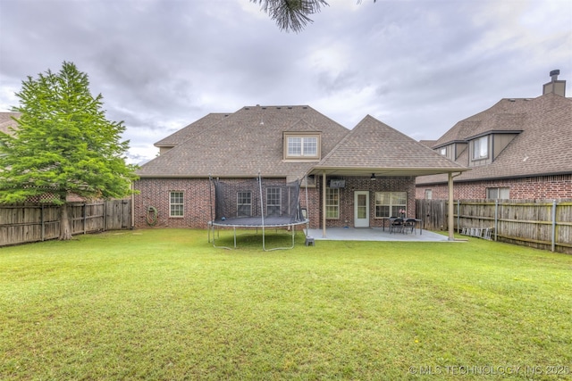 5006 S 164th E Ave, Tulsa, OK 74134 - back of house featuring brick siding, a patio area, a trampoline, and a shingled roof