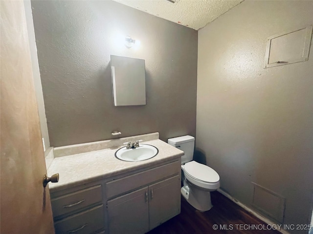 910 Race St, Boswell, OK 74727 - half bathroom with a textured ceiling, toilet, vanity, and wood finished floors