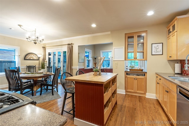 3160 S Owasso Ave, Tulsa, OK 74105 - kitchen with stainless steel dishwasher, butcher block counters, a sink, a breakfast bar area, and a chandelier