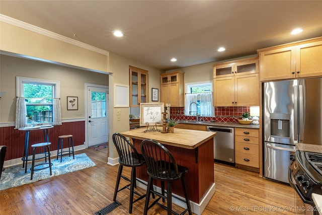 3160 S Owasso Ave, Tulsa, OK 74105 - kitchen featuring stainless steel appliances, butcher block counters, a sink, a breakfast bar, and wood finished floors