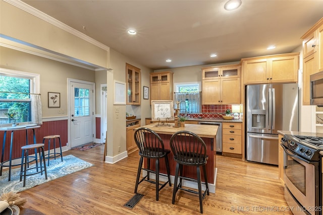 3160 S Owasso Ave, Tulsa, OK 74105 - kitchen featuring appliances with stainless steel finishes, a breakfast bar, a center island, tasteful backsplash, and plenty of natural light