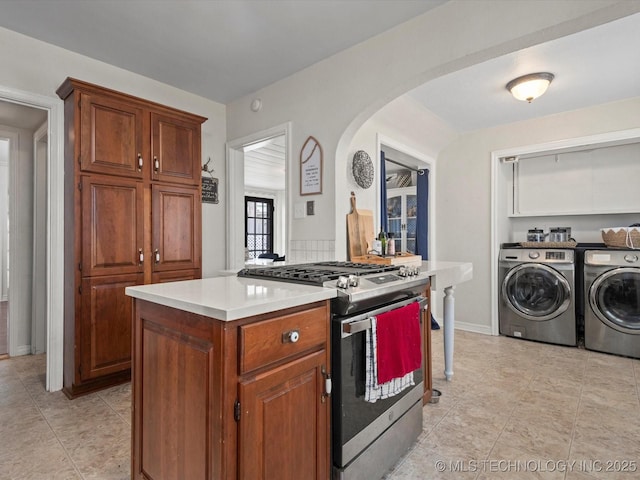 1629 Dewey Ave, Bartlesville, OK 74003 - kitchen with stainless steel range with gas cooktop, washing machine and dryer, arched walkways, light countertops, and light tile patterned flooring