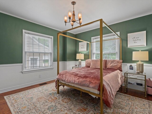 1629 Dewey Ave, Bartlesville, OK 74003 - bedroom with ornamental molding, a wainscoted wall, wood finished floors, and a chandelier