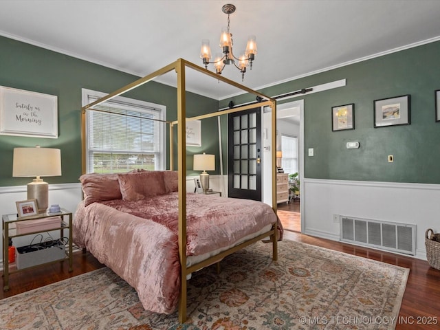 1629 Dewey Ave, Bartlesville, OK 74003 - bedroom with a barn door, ornamental molding, wood finished floors, multiple windows, and a chandelier