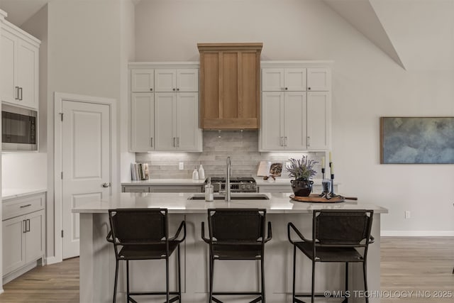 5109 S Everett Dr, Sand Springs, OK 74063 - kitchen with tasteful backsplash, light wood-type flooring, stainless steel microwave, light countertops, and high vaulted ceiling