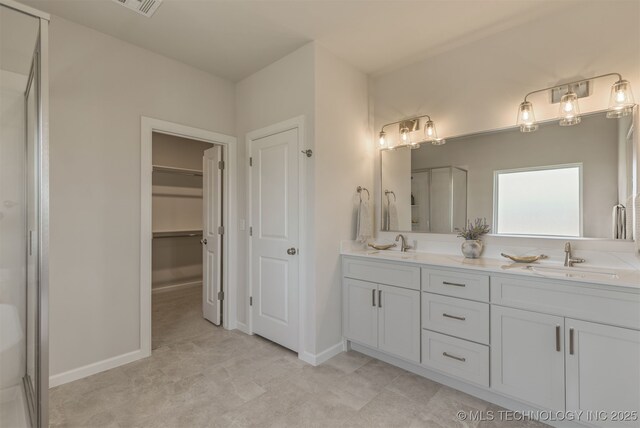 5109 S Everett Dr, Sand Springs, OK 74063 - bathroom featuring double vanity, a shower with door, a spacious closet, and baseboards