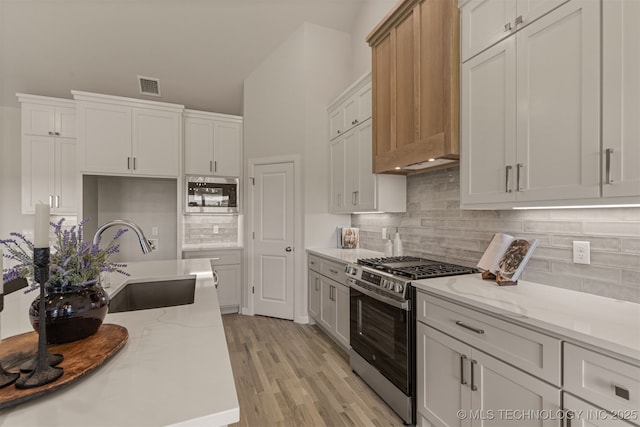5109 S Everett Dr, Sand Springs, OK 74063 - kitchen featuring appliances with stainless steel finishes, a sink, light stone countertops, light wood-style flooring, and decorative backsplash