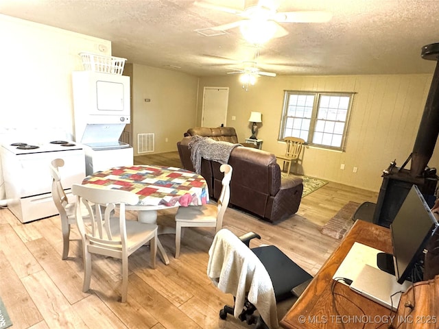 421224 E 1165th Rd, Eufaula, OK 74432 - dining room featuring stacked washer / drying machine, a wood stove, a textured ceiling, light wood-style flooring, and ceiling fan